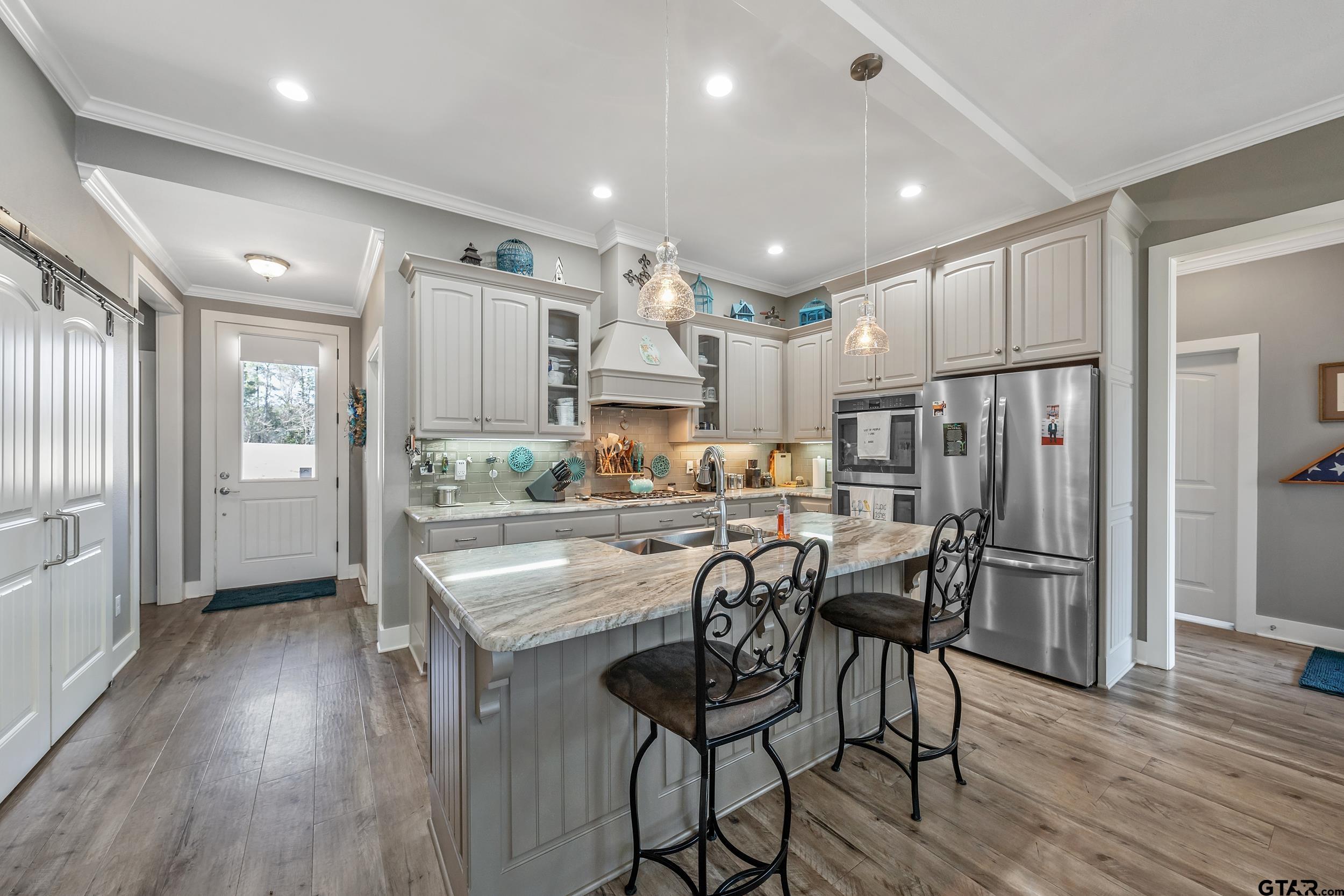 10918 Spring Club Lake Tyler, TX 75706 - Photo 4 of 23 a kitchen with stainless steel appliances kitchen island granite countertop wooden floors and wooden cabinets