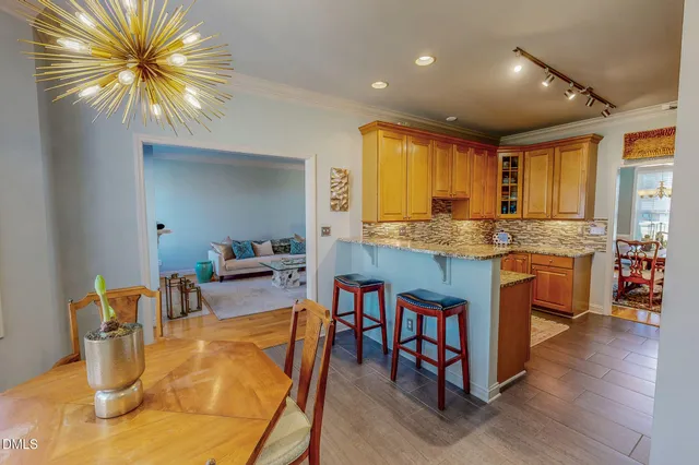 a kitchen with stainless steel appliances granite countertop a sink a stove a dining table and chairs