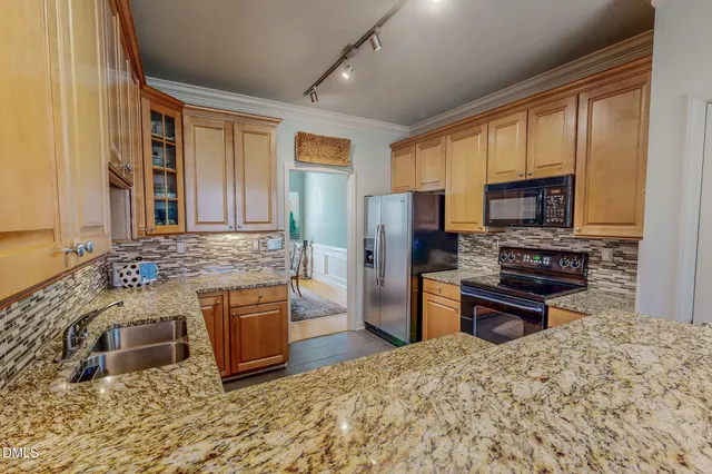 a kitchen with stainless steel appliances granite countertop a stove refrigerator and a sink