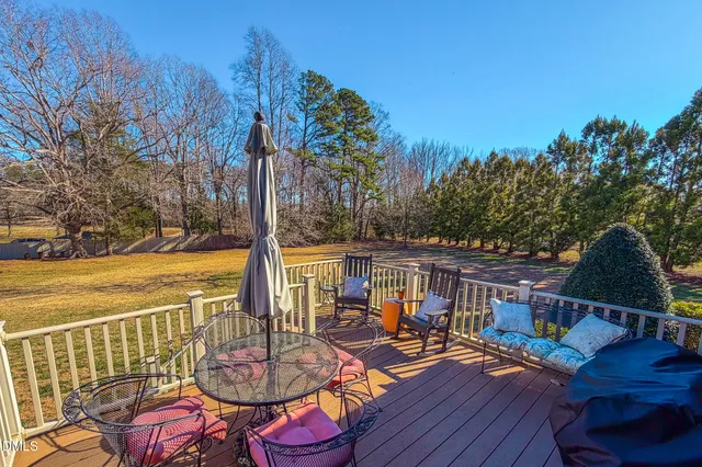 a view of a patio with lawn chairs under an umbrella with wooden floor