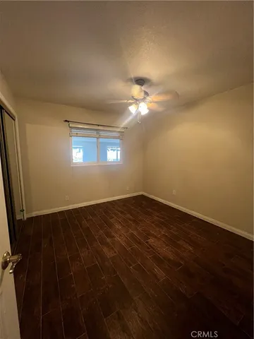 an empty room with wooden floor cabinet and windows