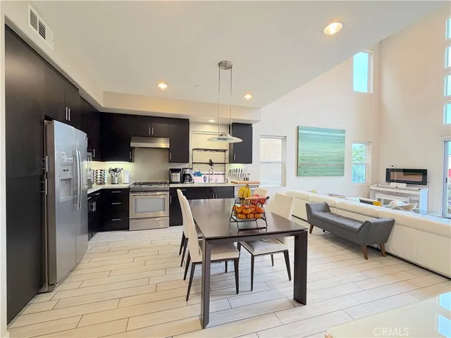 a kitchen with stainless steel appliances granite countertop a refrigerator a stove top oven a sink dishwasher and white cabinets with wooden floor