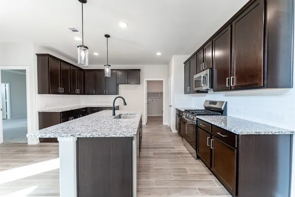 a large kitchen with granite countertop lots of counter space sink and stainless steel appliances