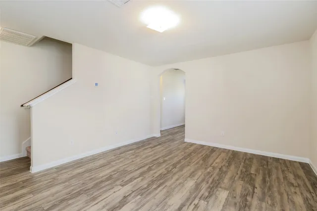 a view of an empty room with wooden floor and closet