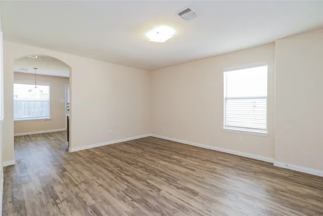 an empty room with wooden floor and windows