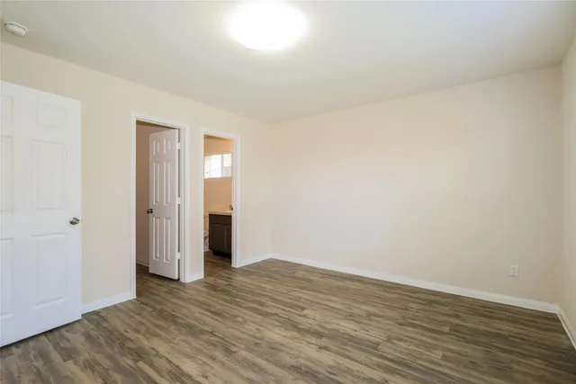 a view of an empty room with wooden floor and closet
