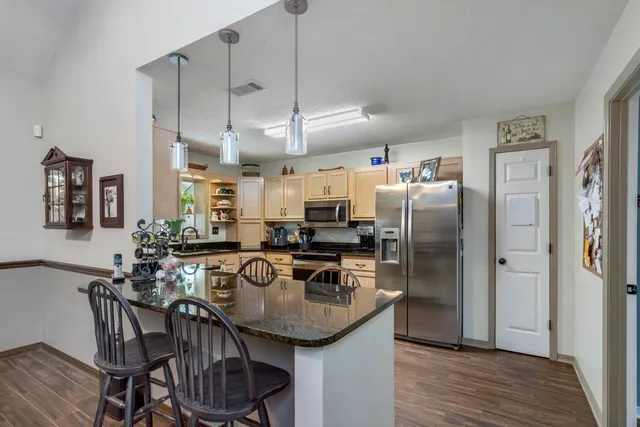 a kitchen with granite countertop white cabinets stainless steel appliances and a window