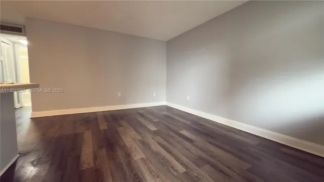 a view of an empty room with wooden floor and windows