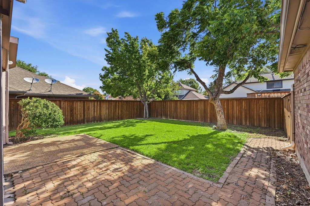 318 Lodge Road Coppell, TX 75019 - Photo 33 of 35 Step outside to a private, tree-shaded backyard with a paved patio and plenty of room for outdoor dining and entertaining.