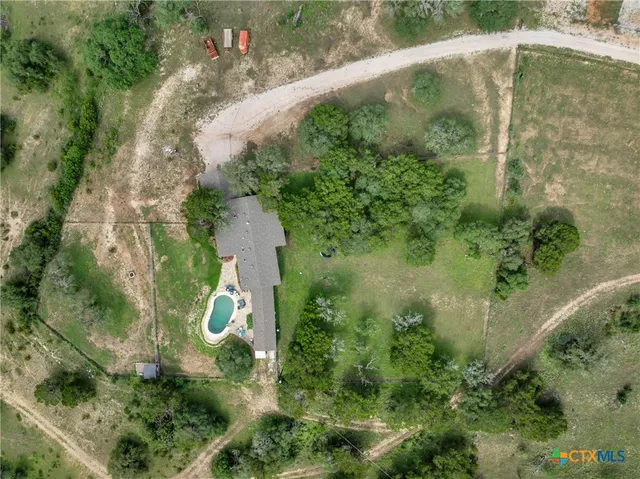 an aerial view of a house with a yard and large trees