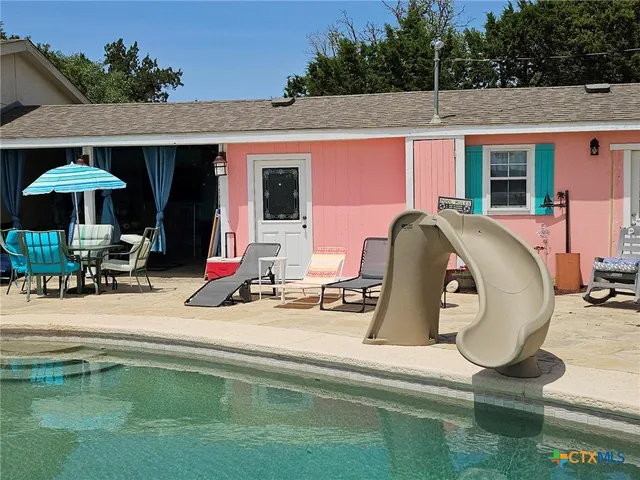 a view of a patio with chairs and tables under an umbrella