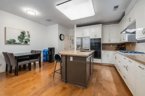 a kitchen with stainless steel appliances granite countertop a table chairs sink and cabinets