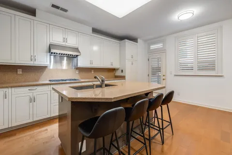 a kitchen with stainless steel appliances granite countertop a table chairs sink and cabinets