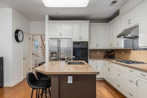 a kitchen with stainless steel appliances a sink a stove a refrigerator and cabinets
