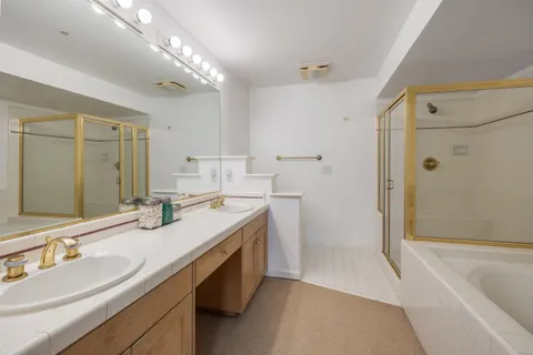 a bathroom with a sink double vanity granite tub shower and a mirror