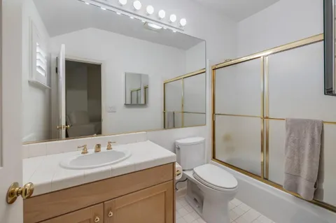 a bathroom with a sink a toilet a mirror and shower