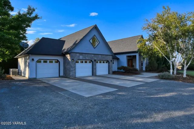 a view of a house with brick walls plants and large tree