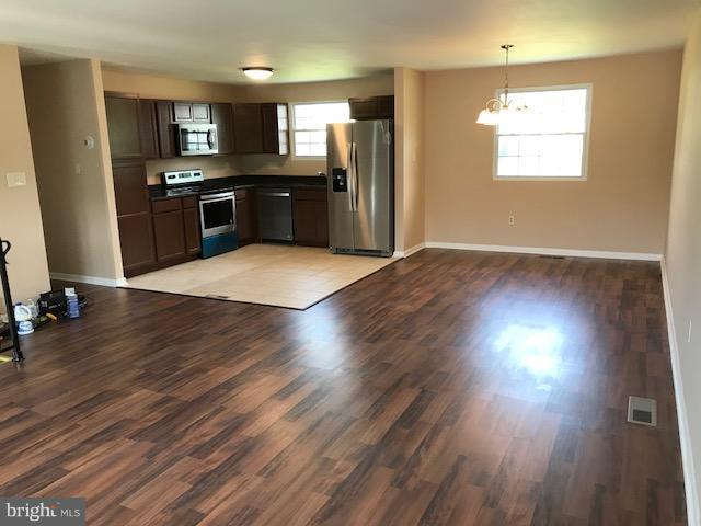 3901 Sadie Road Randallstown, MD 21133 - Photo 3 of 28 a kitchen with stainless steel appliances granite countertop a stove top oven a refrigerator with wooden floors