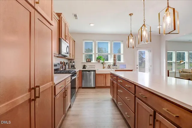 a kitchen with stainless steel appliances granite countertop a sink a stove a refrigerator a center island and a wooden floor