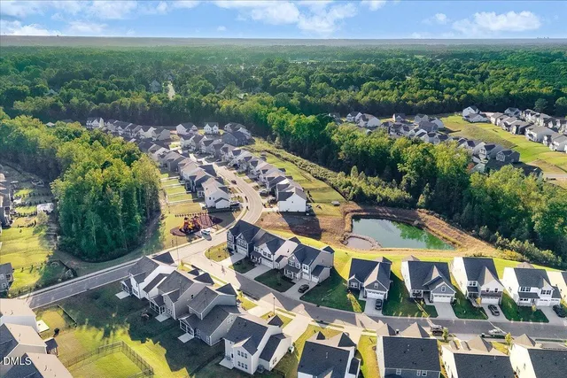 a view of a swimming pool with table and chairs potted plants and large tree