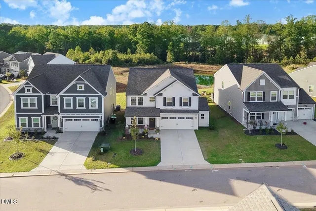 an aerial view of residential houses with outdoor space and trees