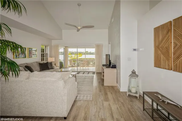 a living room with furniture a potted plant and open kitchen view