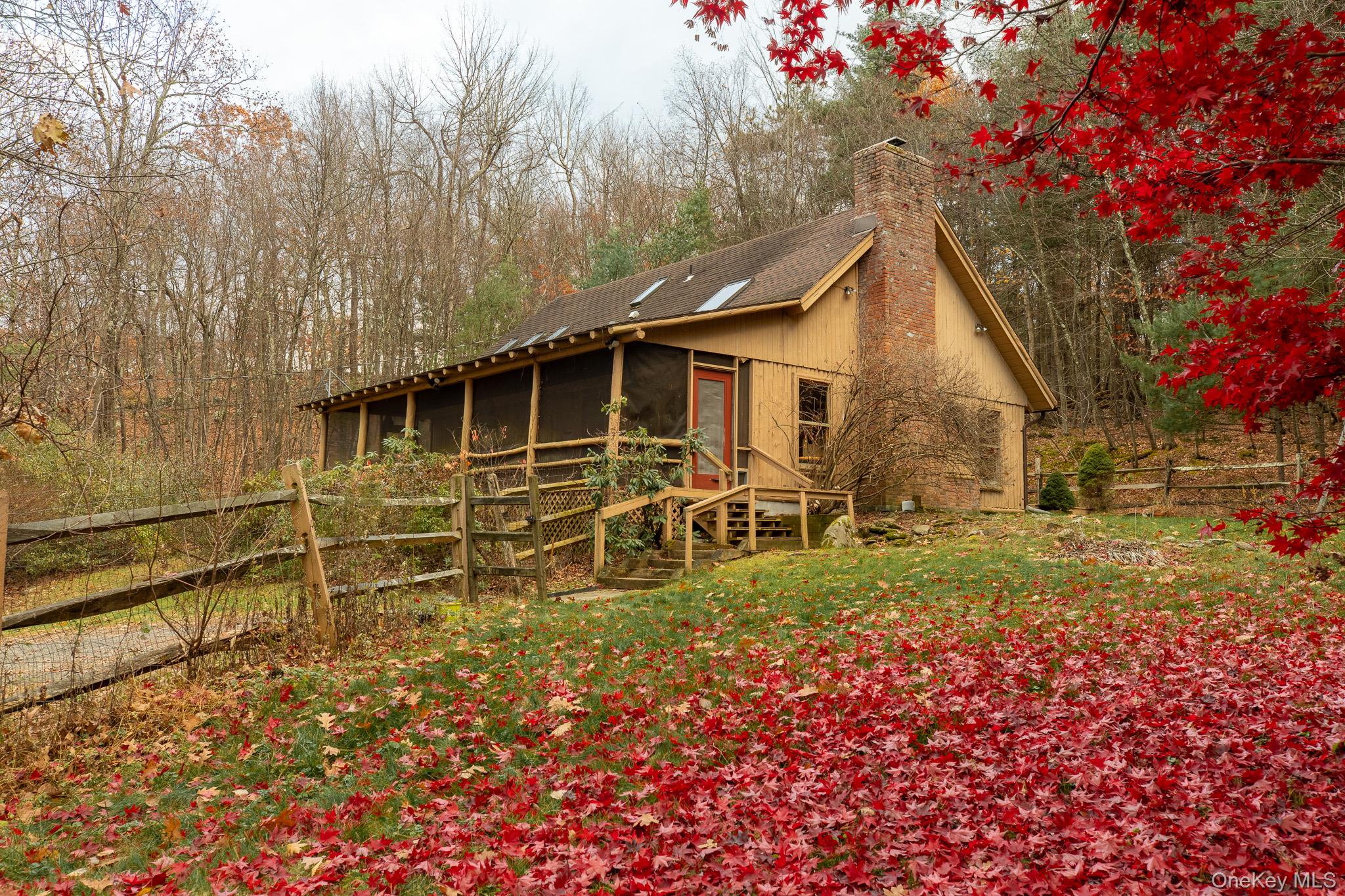 View of side of property with a chimney, a sunroom, and a view of trees