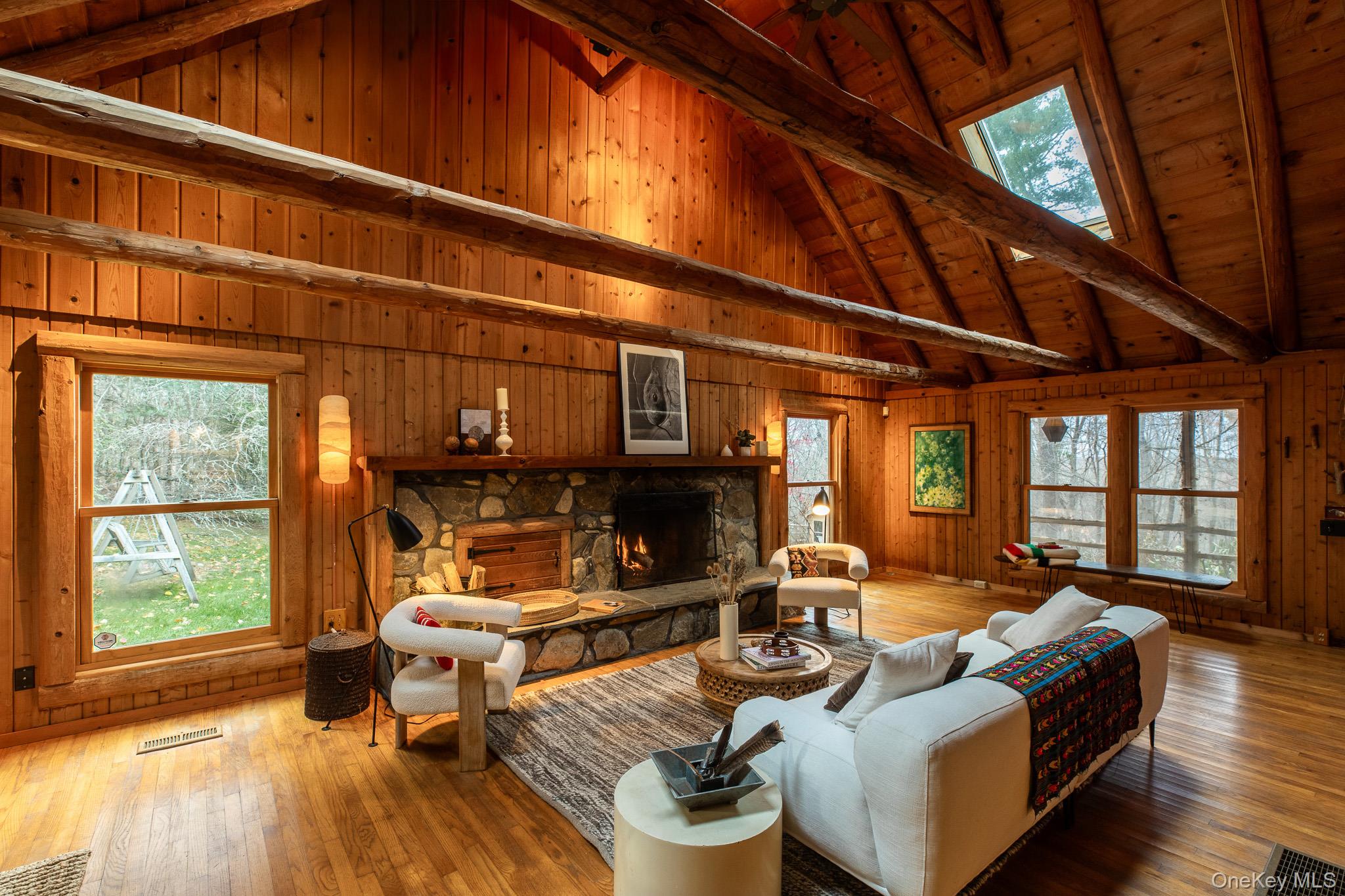 79 Torre Rock Road Red Hook, NY 12571 - Photo 6 of 33 Living area with a stone fireplace, wood-type flooring, wooden walls, high vaulted ceiling, and a wooden ceiling with exposed beams
