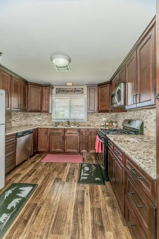 a kitchen with stainless steel appliances granite countertop a stove sink cabinets and wooden floor