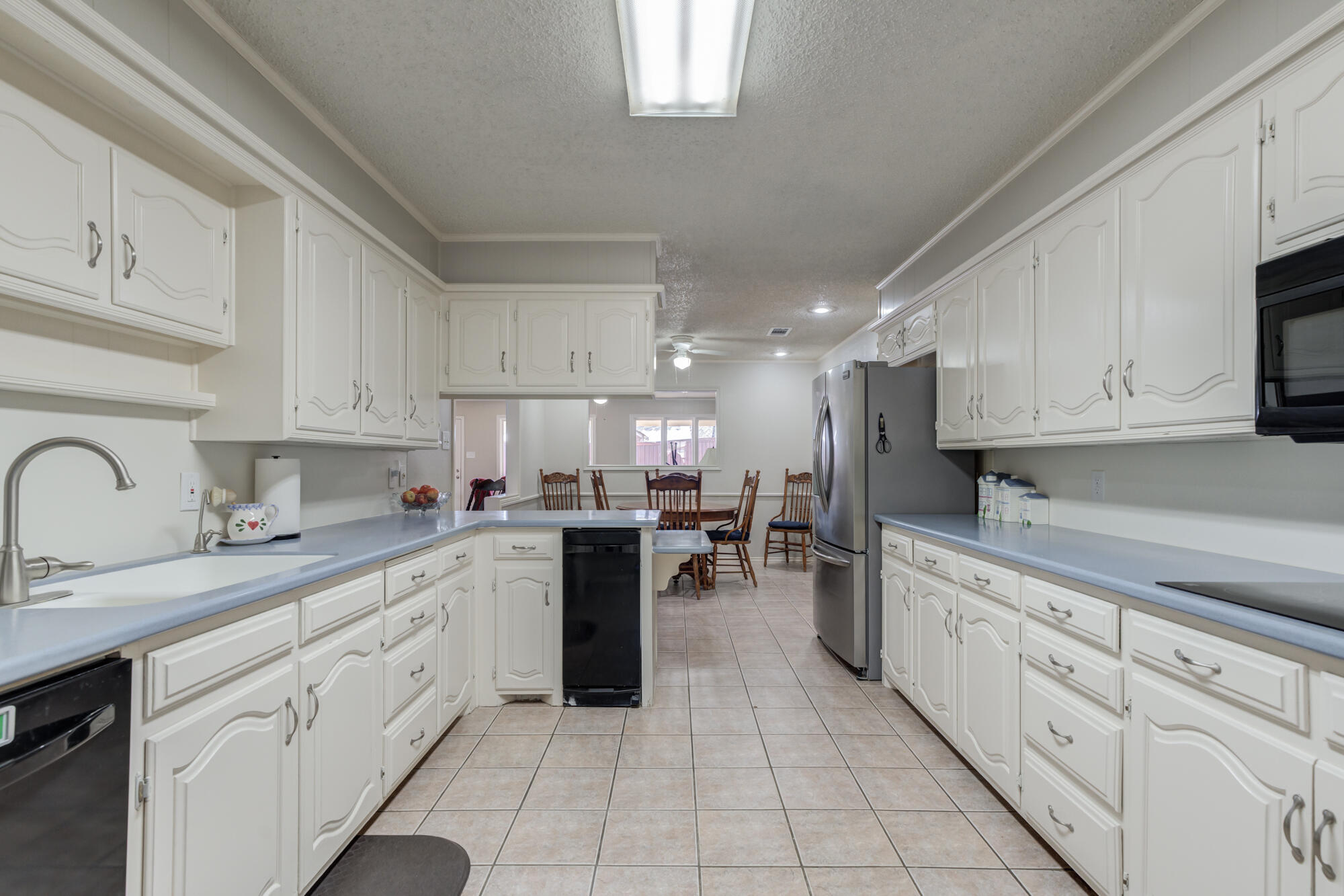 4809 78th Street Lubbock, TX 79424 - Photo 11 of 48 a kitchen with kitchen island granite countertop a sink a stove oven and white cabinets