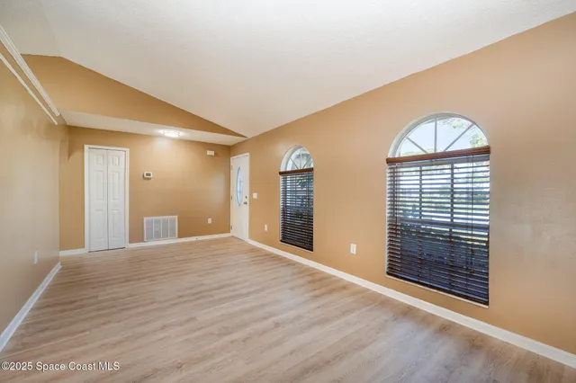 a view of an empty room with wooden floor and a window