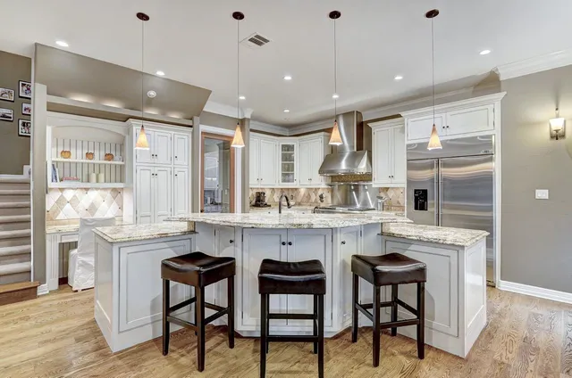 a kitchen with stainless steel appliances granite countertop a table chairs sink and cabinets