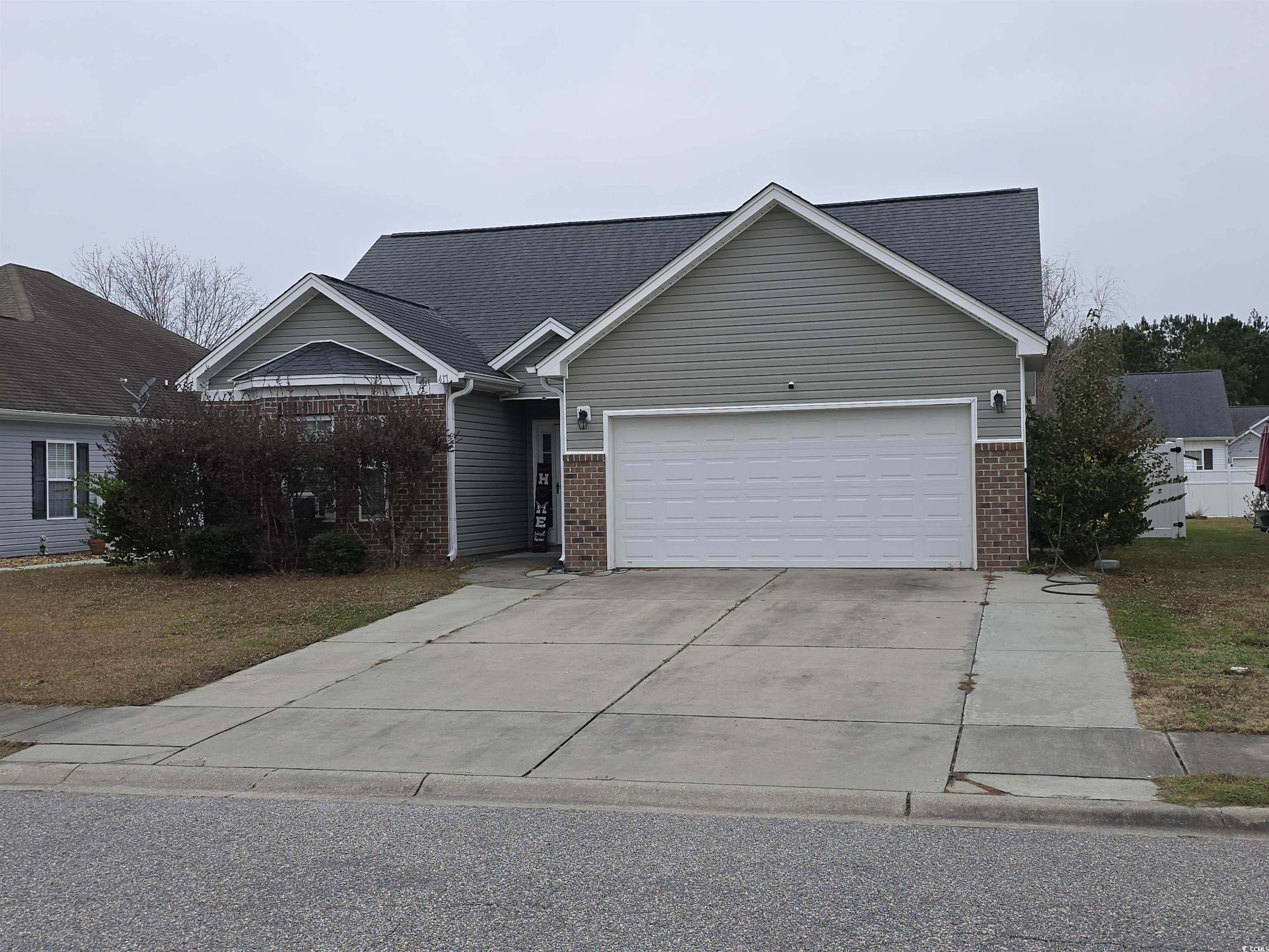 View of front of property featuring brick siding, driveway, an attached garage, and a front lawn