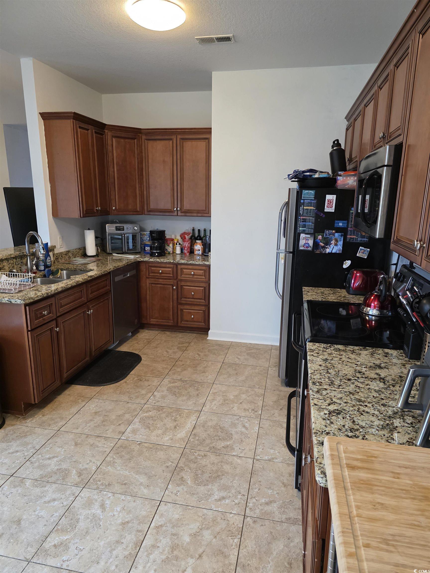 417 Cassian Way Myrtle Beach, SC 29588 - Photo 10 of 13 Kitchen with black range, light stone counters, stainless steel microwave, dishwashing machine, and light tile patterned flooring