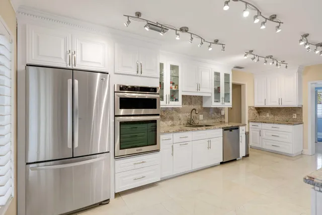 a kitchen with white cabinets and stainless steel appliances