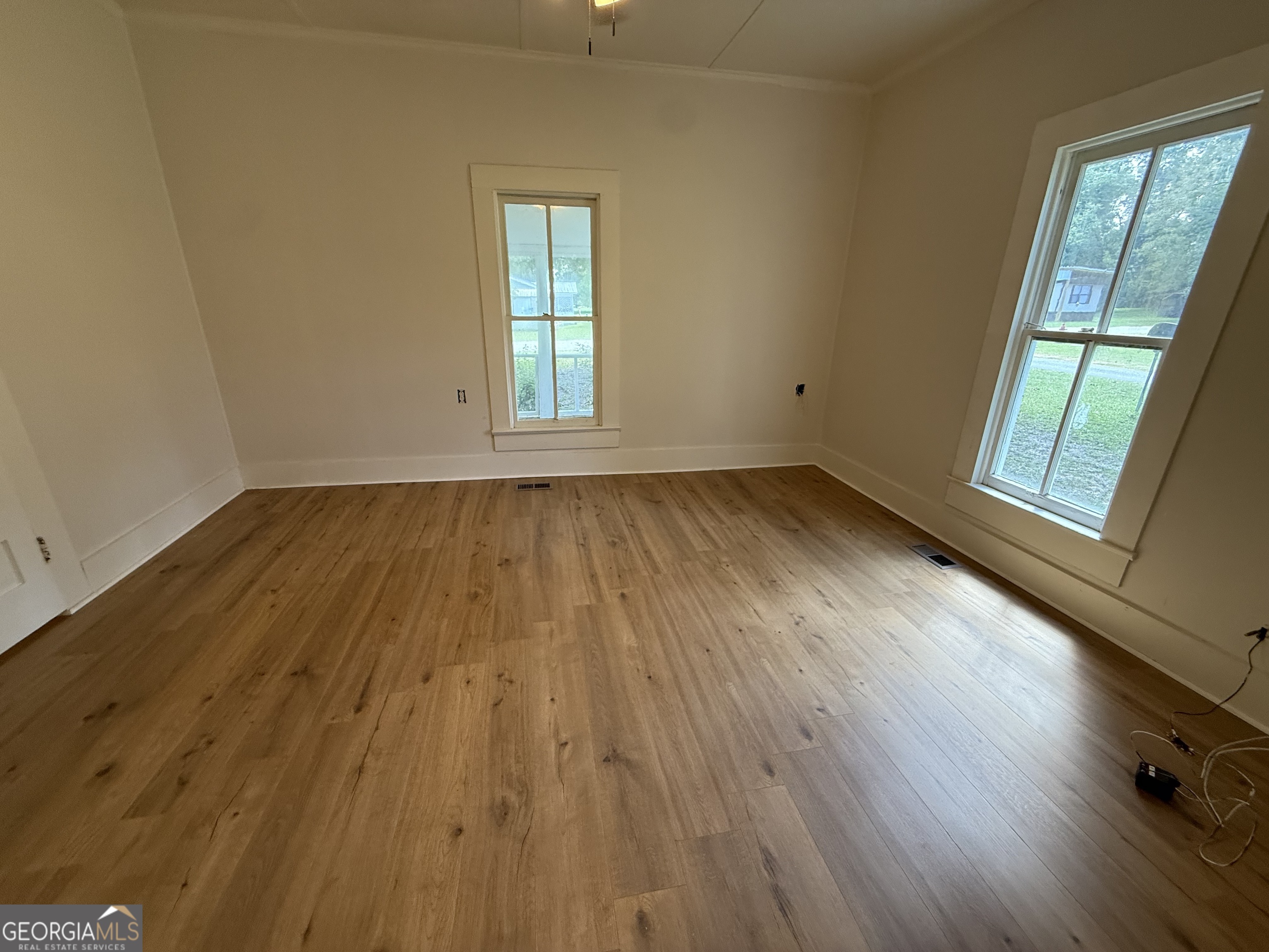 604 Shy Street Dexter, GA 31019 - Photo 17 of 36 an empty room with wooden floor and windows