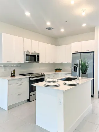 a kitchen with stainless steel appliances granite countertop a sink a stove top oven a counter space and cabinets