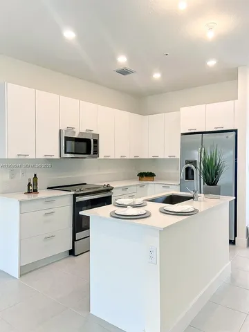 a kitchen with stainless steel appliances granite countertop a sink a stove top oven a counter space and cabinets