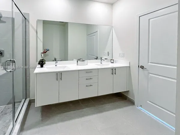 a bathroom with a double vanity sink a mirror and a bathtub