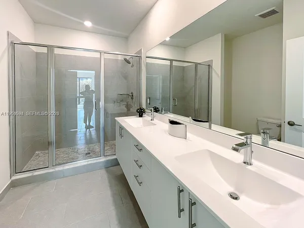 a bathroom with a double vanity sink mirror and shower