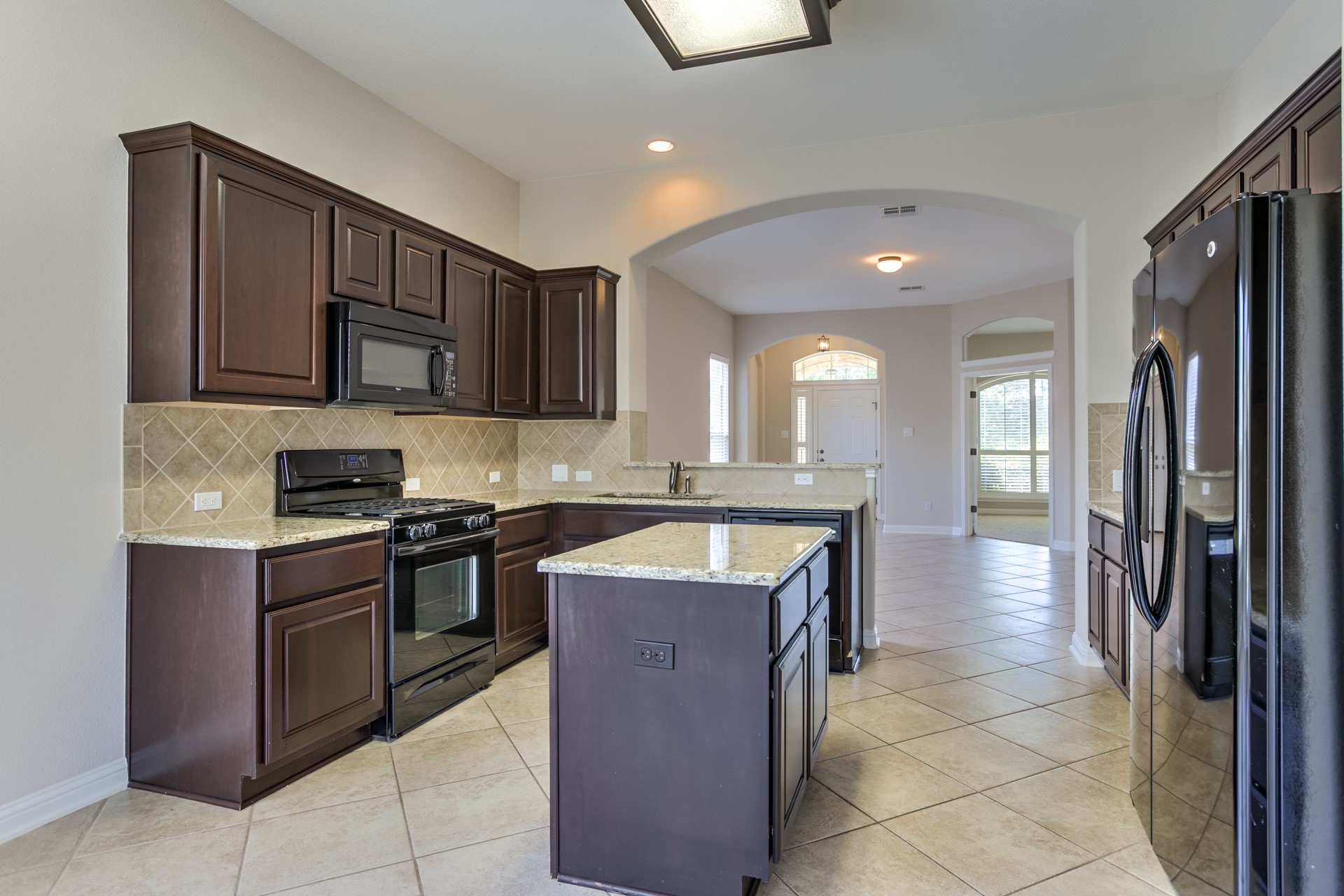 3667 Rosalina Loop Round Rock, TX 78665 - Photo 11 of 26 Kitchen featuring black appliances, dark wood finish cabinetry, light stone countertops, light tile patterned floors, and recessed lighting