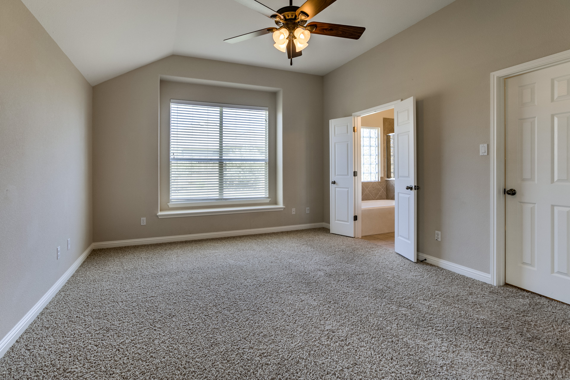 3667 Rosalina Loop Round Rock, TX 78665 - Photo 14 of 26 Unfurnished bedroom featuring light colored carpet, ensuite bath, a ceiling fan, and vaulted ceiling