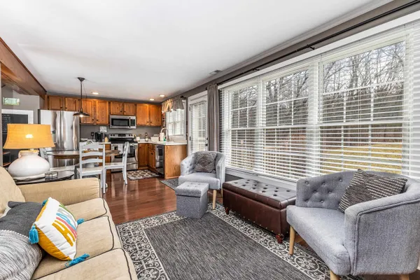 a kitchen with stainless steel appliances granite countertop a stove a refrigerator a microwave a dining table and chairs with wooden floor