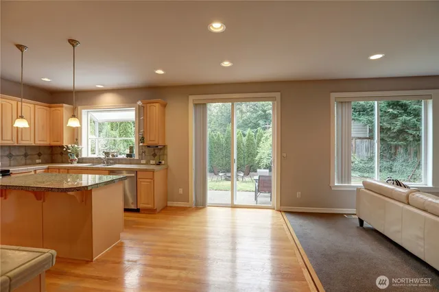 a open kitchen with stainless steel appliances granite countertop a refrigerator a sink dishwasher a stove and white countertops with wooden floor