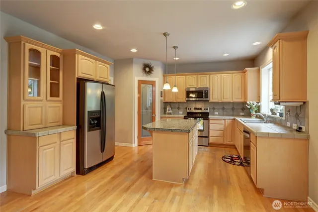 a kitchen with stainless steel appliances granite countertop a refrigerator a stove top oven and a refrigerator