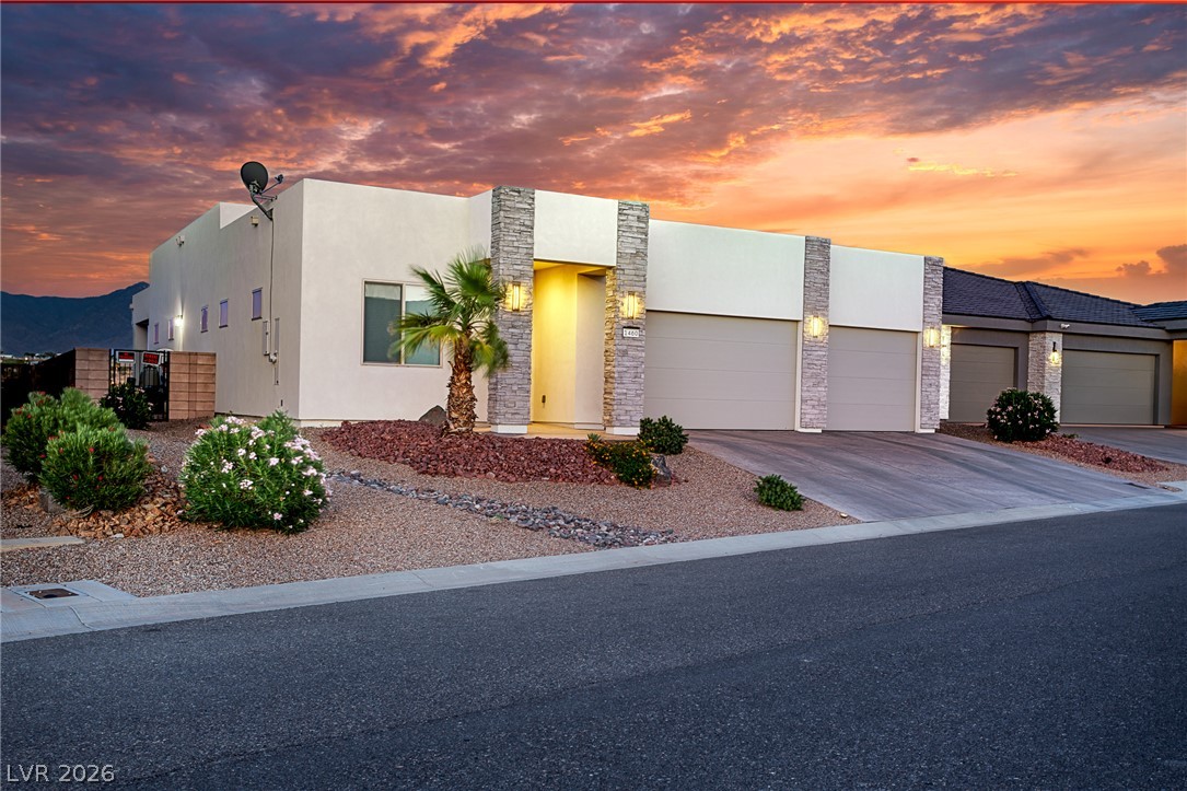 1460 Blue Ridge Trail Mesquite, NV 89027 - Photo 33 of 39 Modern desert home with elegant stone accents under a dramatic sunset sky.