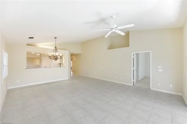 an empty room with chandelier fan and fireplace