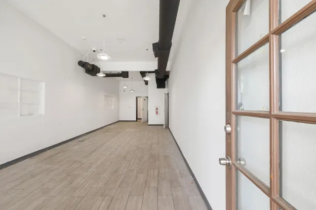 a view of an empty room with wooden floor and windows