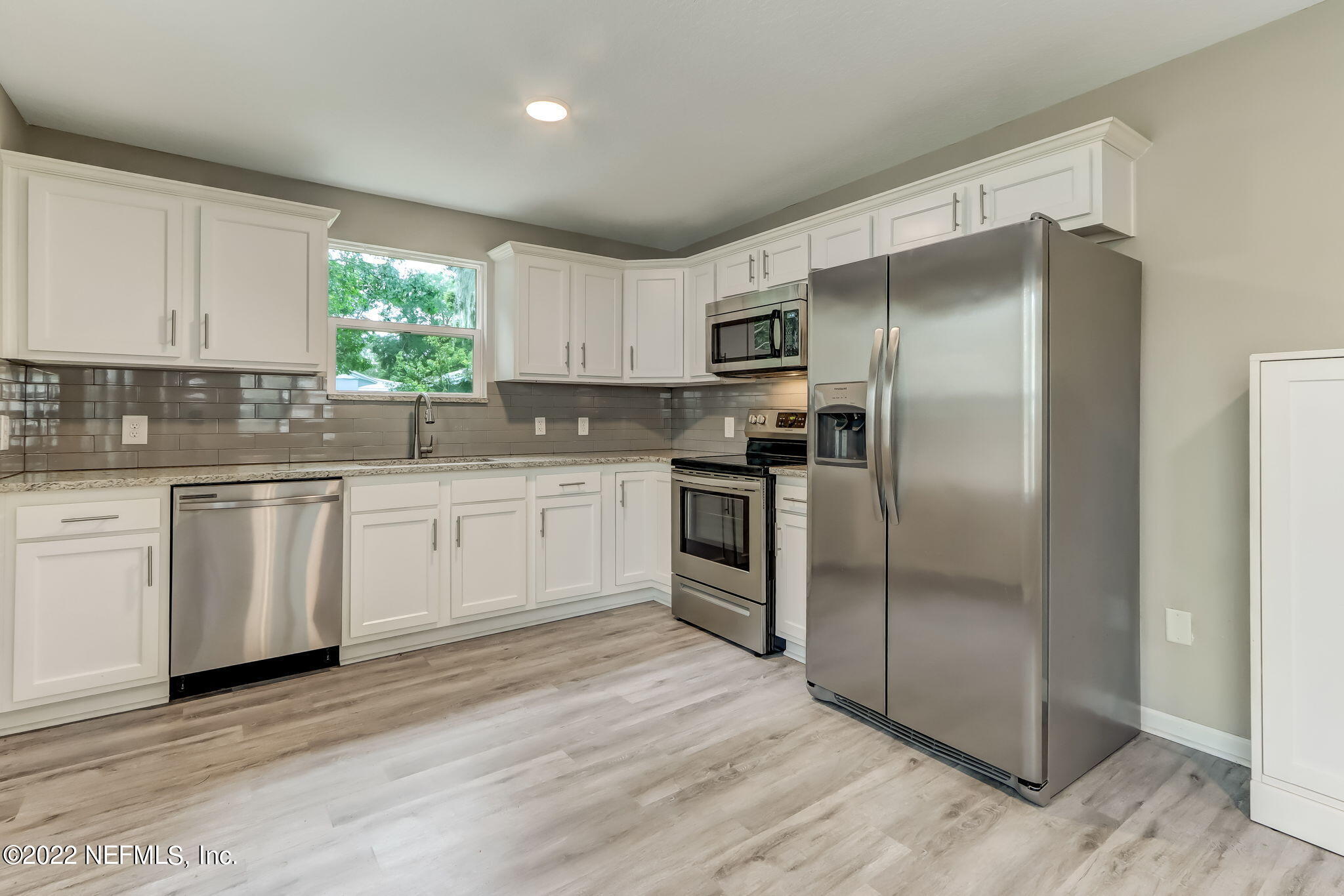 5218 Sunderland Road Jacksonville, FL 32210 - Photo 7 of 23 a kitchen with white cabinets stainless steel appliances and a window