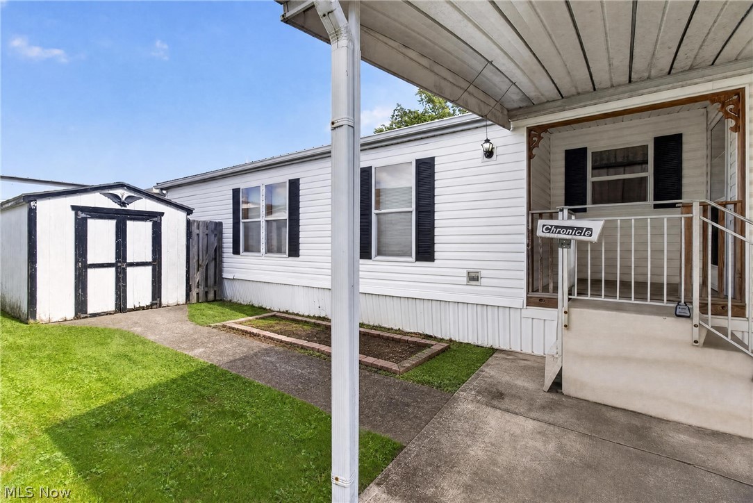 35157 Center Ridge Road, Unit 153 North Ridgeville, OH 44039 - Photo 2 of 35 White siding exterior with black shutters, covered concrete carport, concrete front entry steps with metal handrails, and a covered front porch with exterior lighting